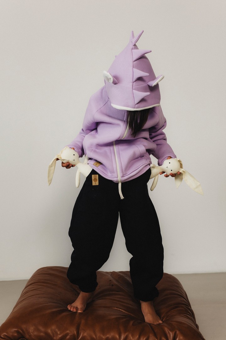 Dziewczynka w liliowej bluzie dziecięcej rozpinanej z uszami jeża i kolcami oraz dresach czarnych typu balloon – na modelce